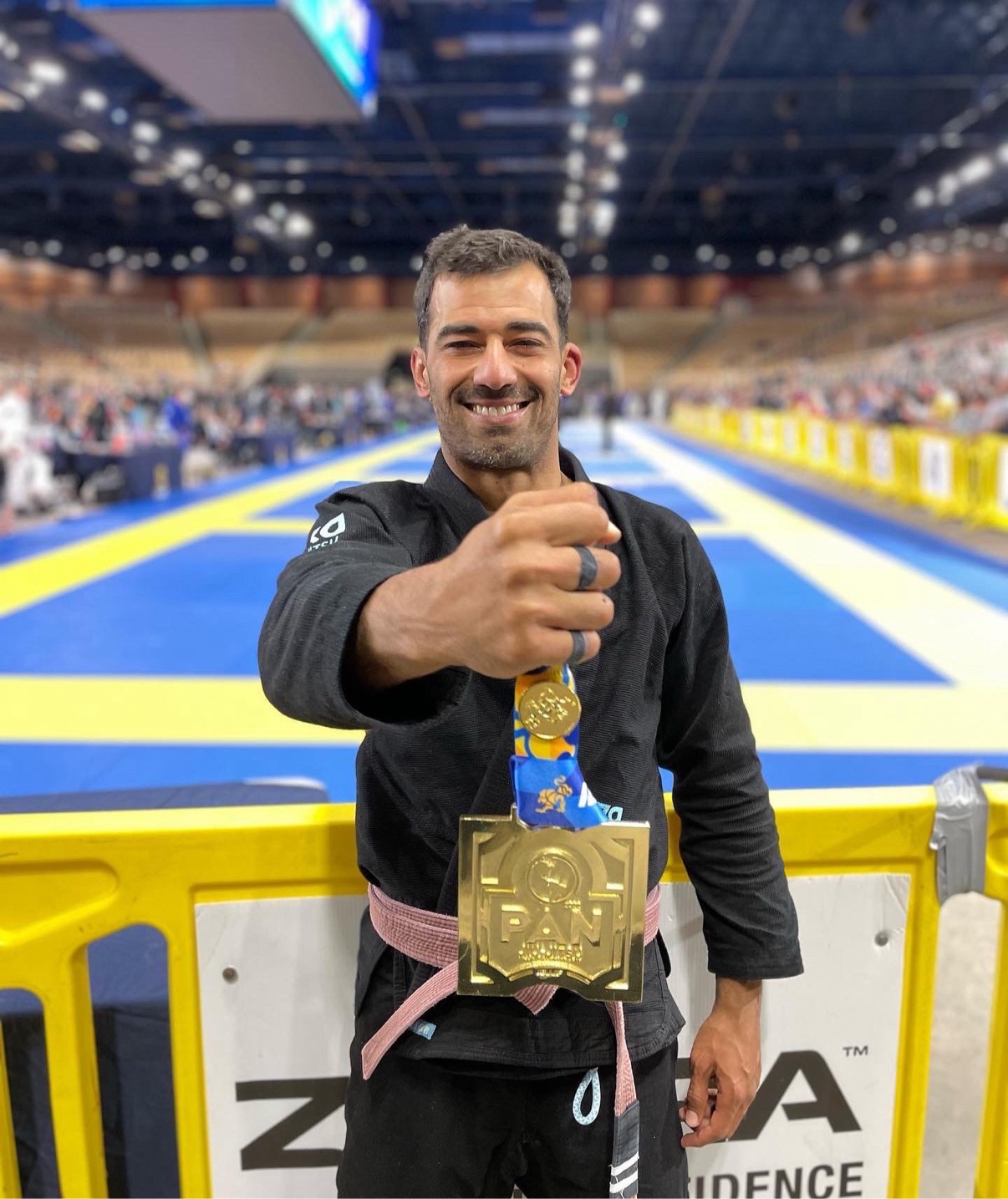 Deivid Dias holding up a large IBJJF Pan gold medal in a black gi