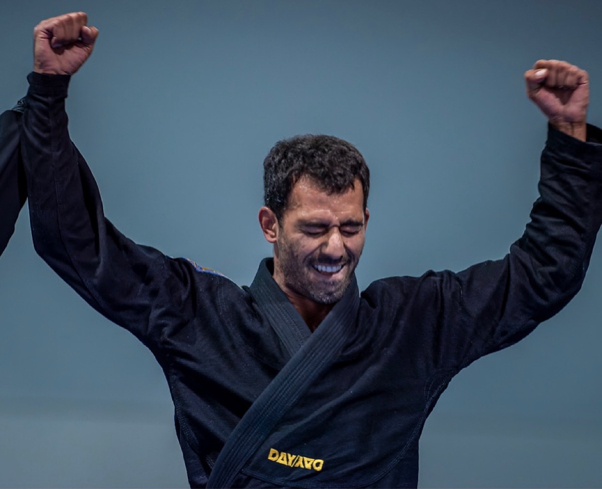 Deivid Dias celebrating with both arms raised in a black gi